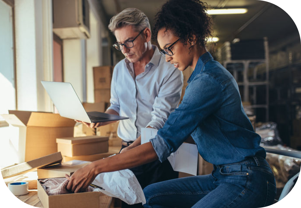 Woman packing the product in box with man working on laptop