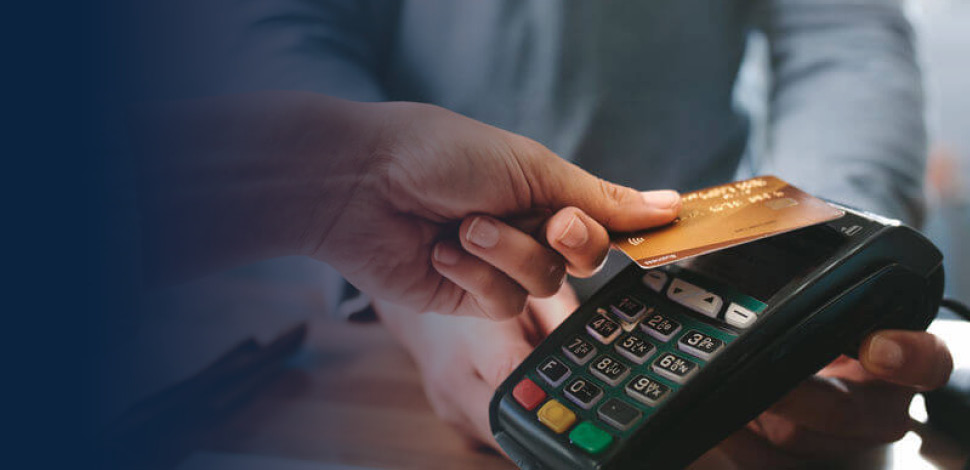 Hand of customer using a credit card to pay at terminal.