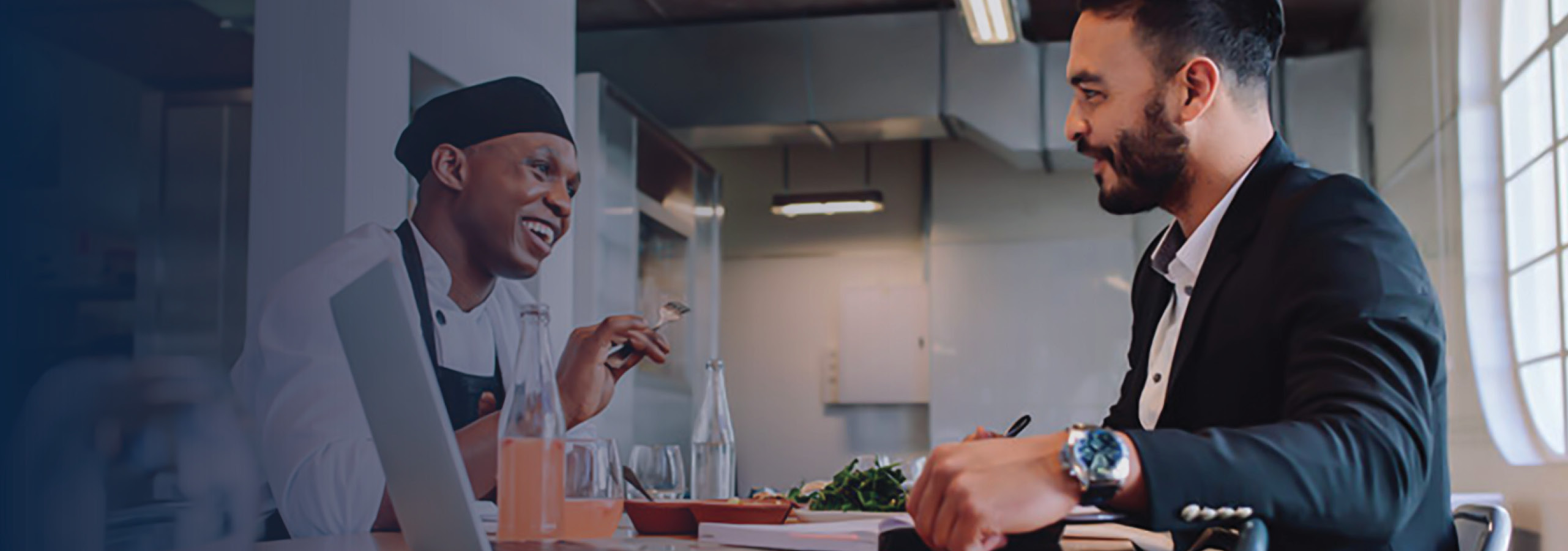 Smiling restaurant manager sitting at table and talking with chef