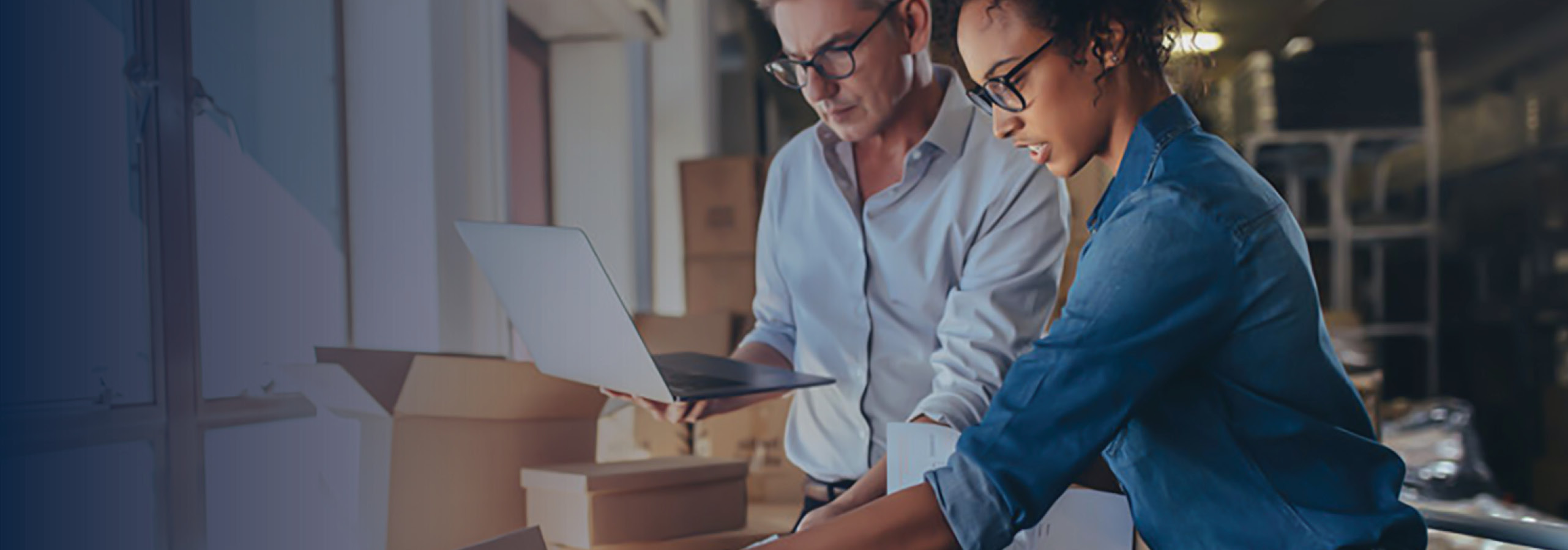 Woman packing the product in box with man working on laptop.