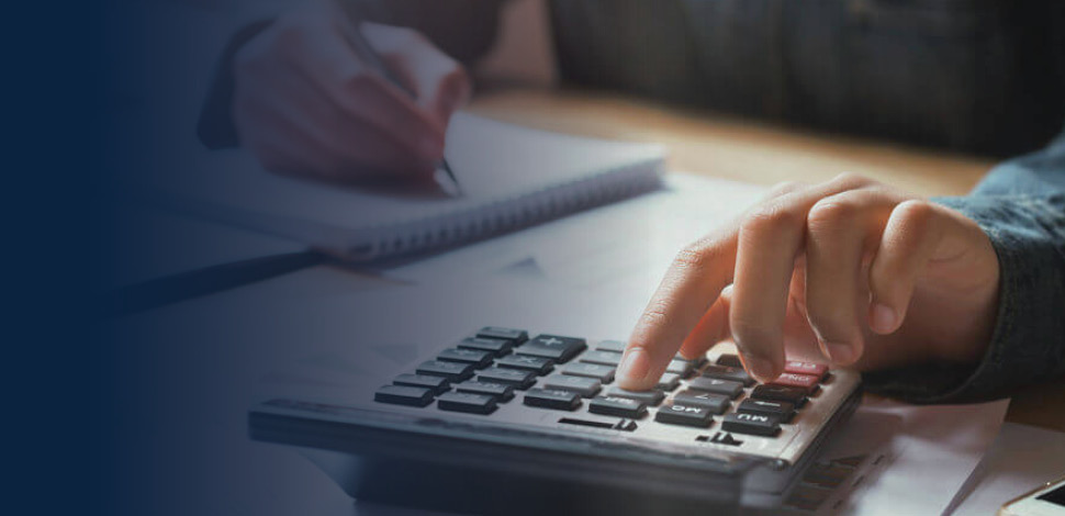 Hand using calculator with paperwork in the background