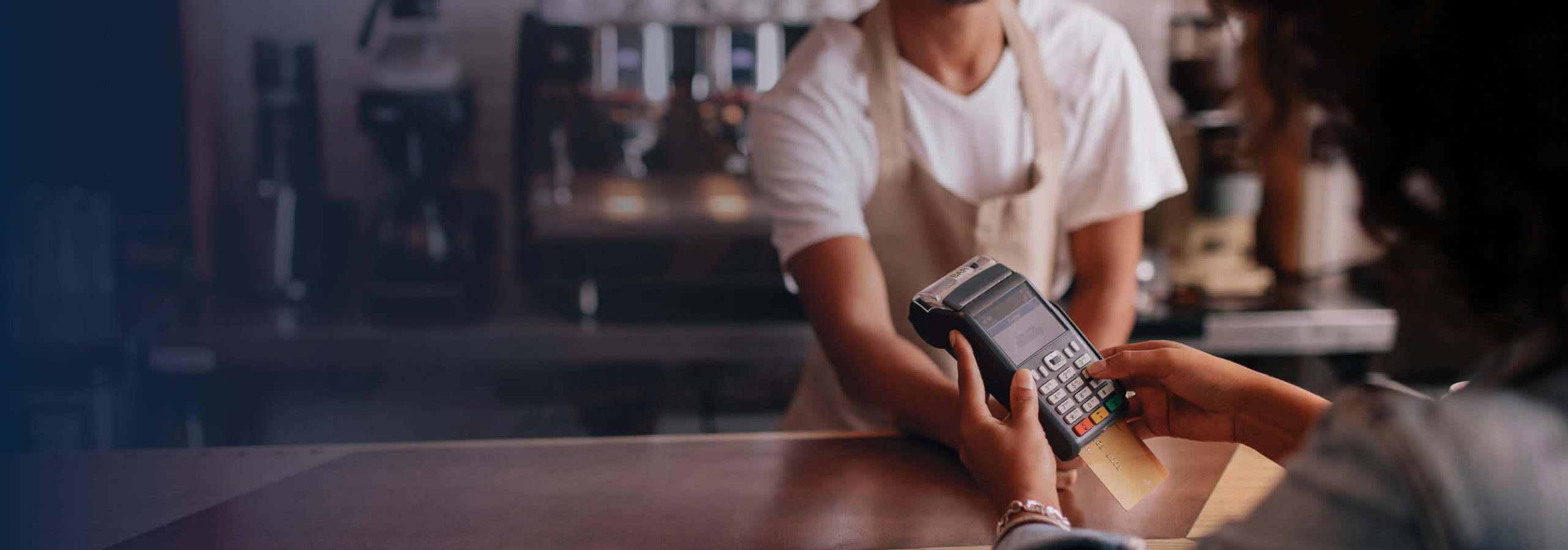 Male coffee shop employee passing a customer the payment terminal.