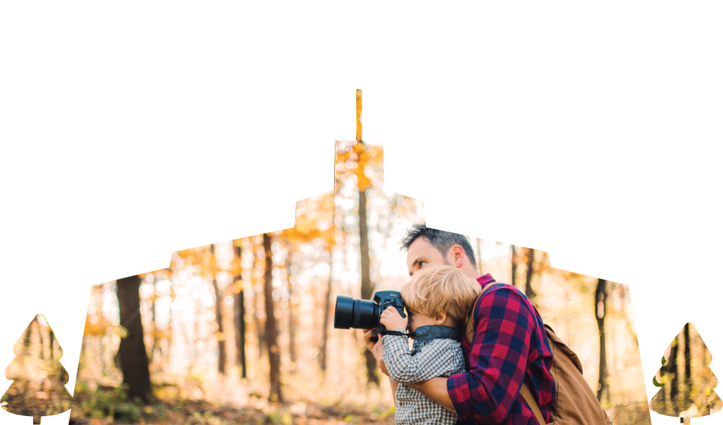 A father and a toddler son in an autumn forest taking pictures with a camera