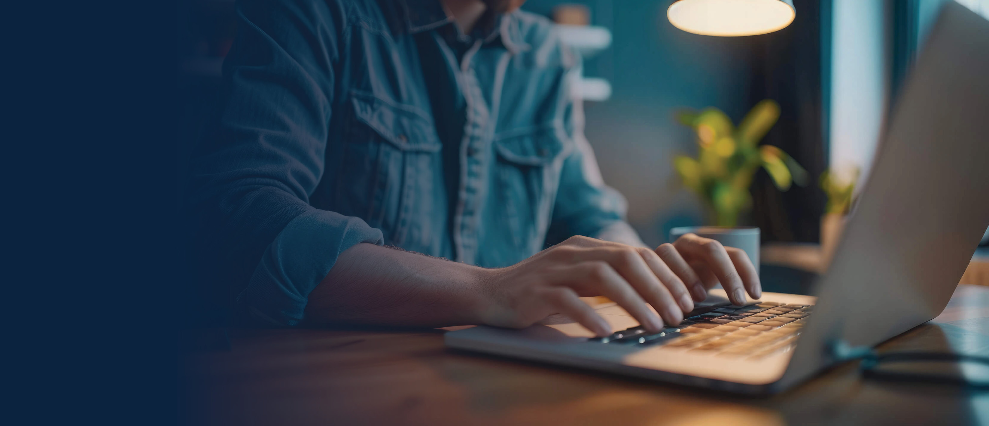 A man using a laptop at home, his face is not visible.