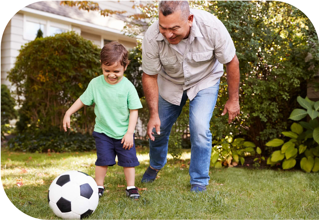 Father and son playing soccer outside.