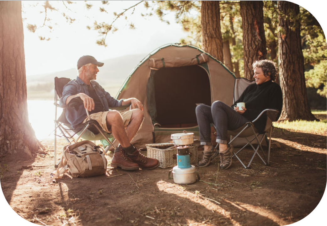 Happy senior couple sitting in chairs by tent at campsite