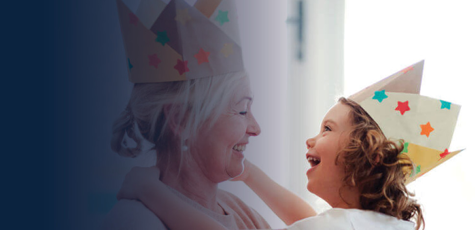 Grandmother and granddaughter embracing, wearing paper crowns