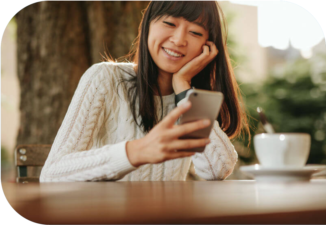 Young woman sitting at outdoor cafe while looking at cellphone