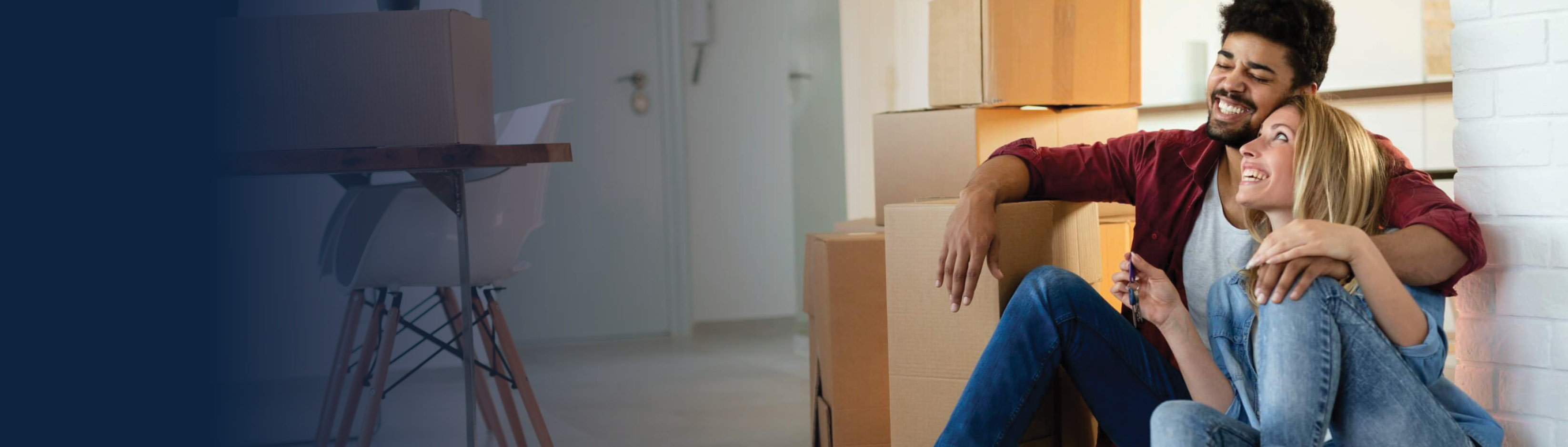 Couple sitting in new home surrounded by boxes.
