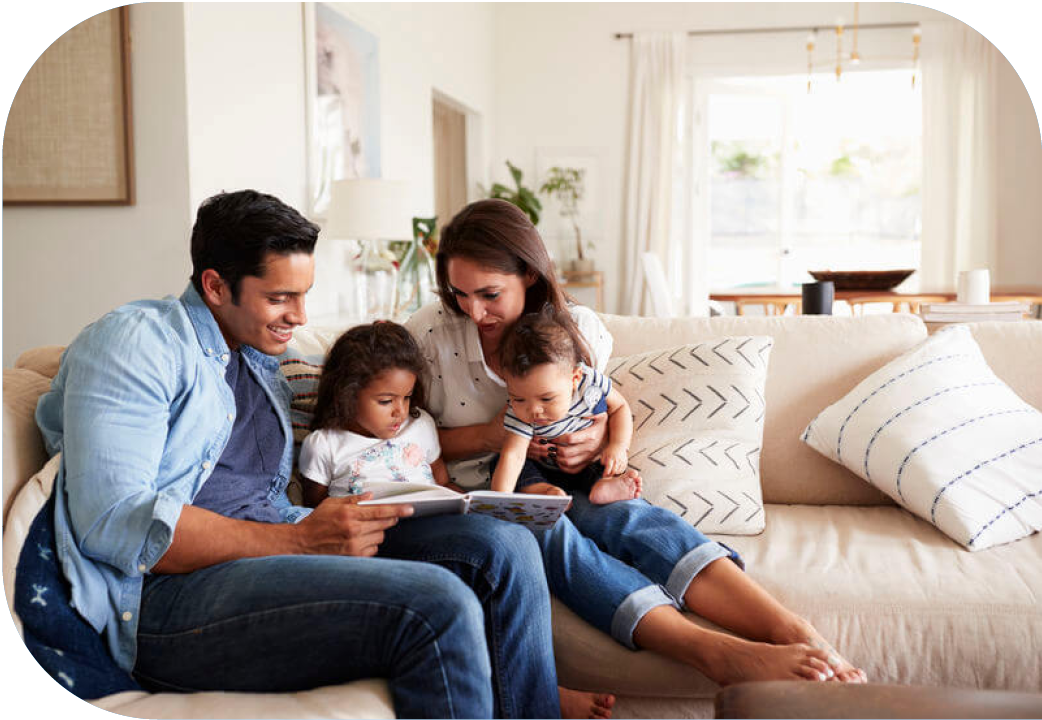 Young family at home reading a book together.