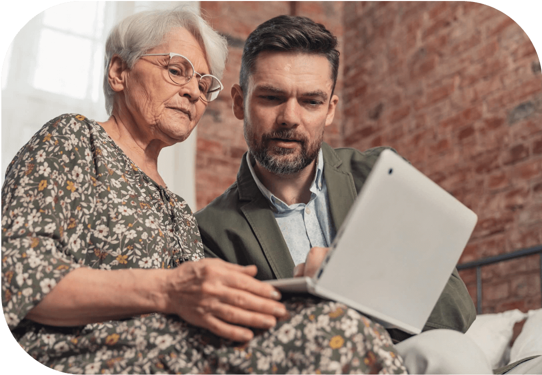 A man and an older woman looking at a laptop together.