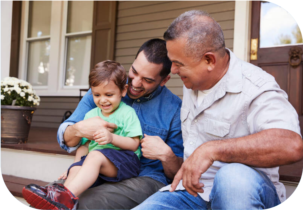 Young child sitting with father and grandfather on front step of house