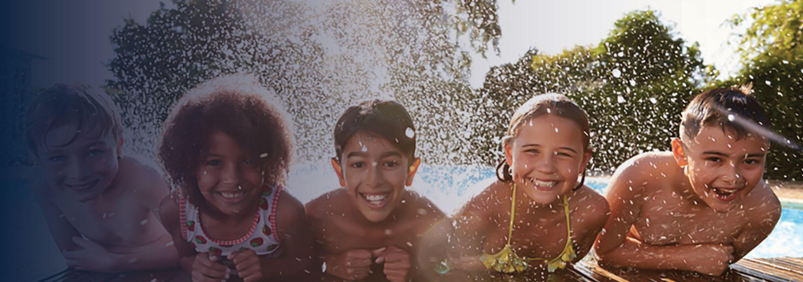 Children leaning over edge of dock, with feet in the water, splashing water