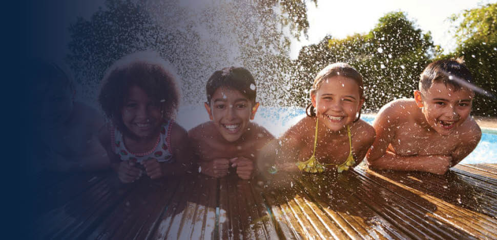 Children leaning over edge of dock, with feet in the water, splashing water