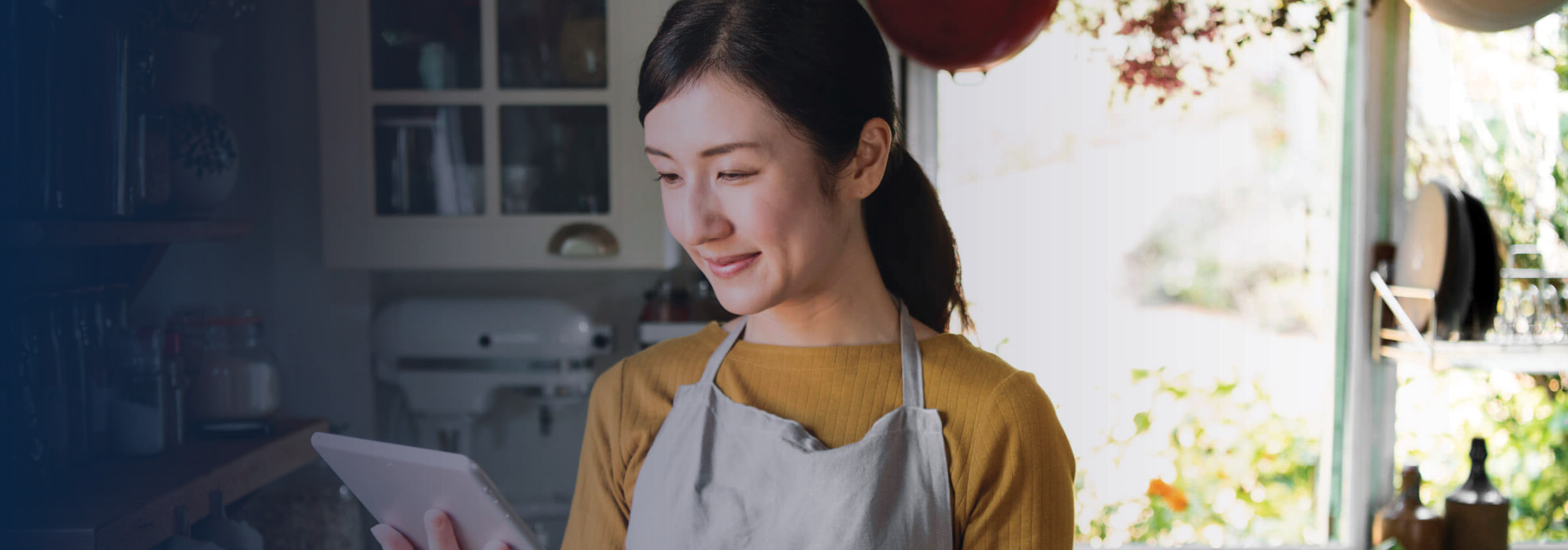 Woman in kitchen checking a recipe on tablet