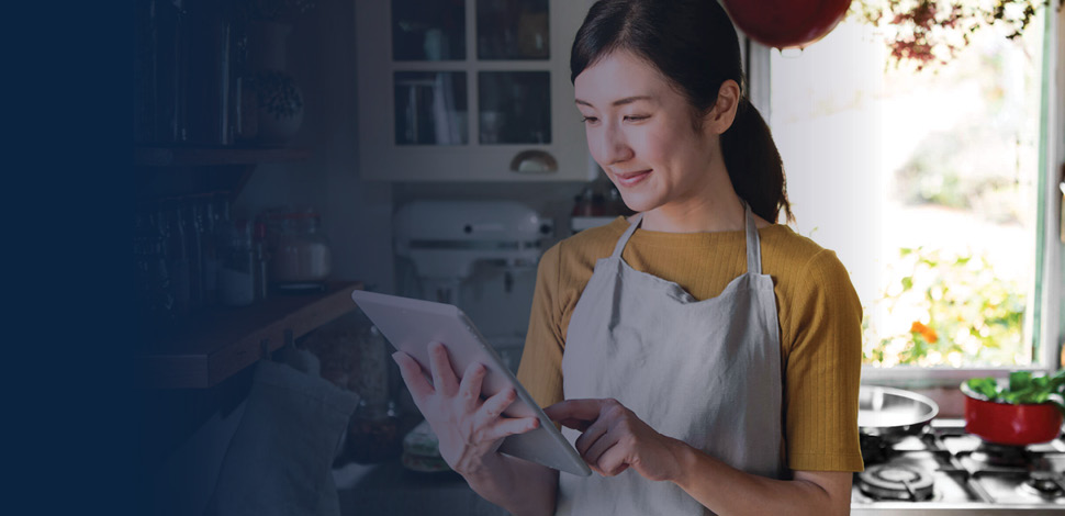 Woman in kitchen checking a recipe on tablet