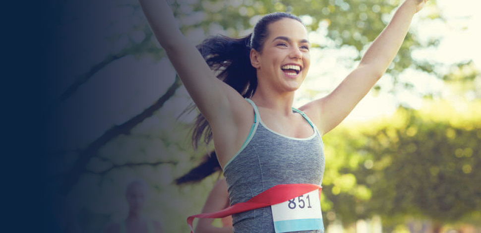 Woman finishing a marathon race, hands raised in celebration
